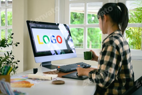 Preview: Young female graphic designer using a pen tablet and computer to design a colorful logo