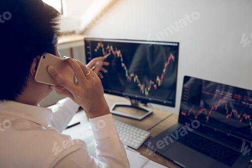 Preview: Agent trader man talking at telephone and checking business stock data on computer in office room.