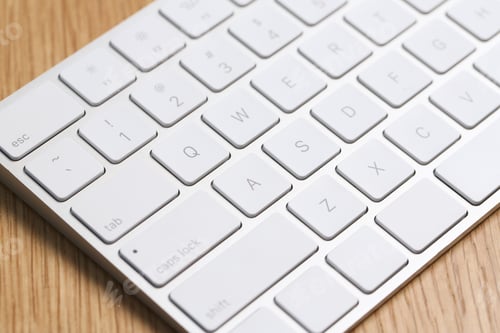 Preview: Modern white wireless keyboard on wooden table, closeup