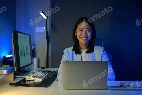 Preview: Portrait of young hardworking businesswoman working overtime during the night in her office room.