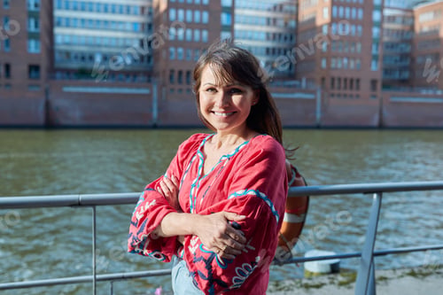 Preview: Mature smiling woman in embroidered shirt looking at camera, outdoor