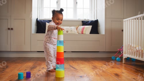 Preview: Standing Female Toddler At Home Playing With Stacking Plastic Toy