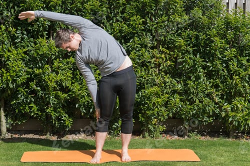 Preview: Young fit male practicing yoga and stretching outdoors
