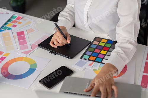 Preview: Creative Graphic Designer Working with Color Palettes and Digital Tablet in Modern Office