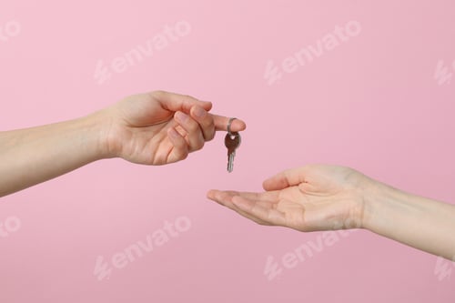 Preview: Female hands with a key on a pink background