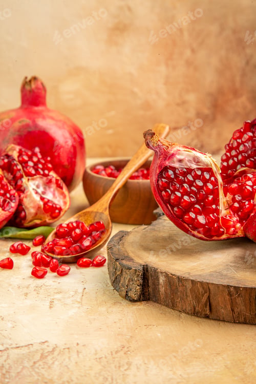 Preview: Front view (pomegranate) 2 pomegranates and slices put on the stump with a bowl and a spoon of seed