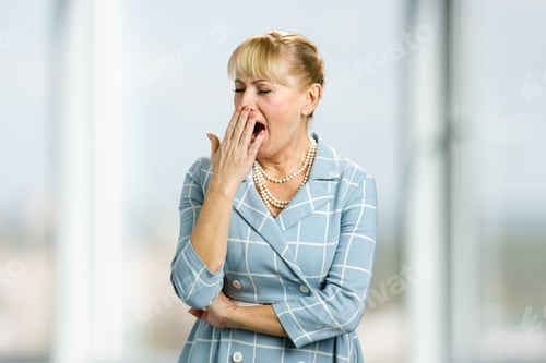 Preview: Yawning mature woman, blurred background.