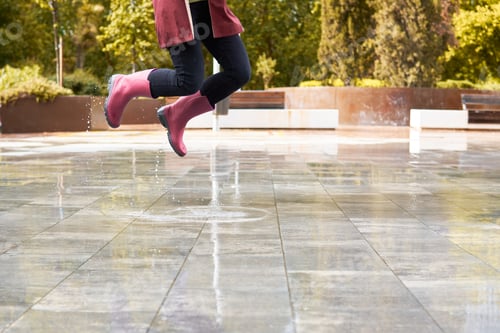 Preview: Happy woman with boots jumpint in a rain puddle