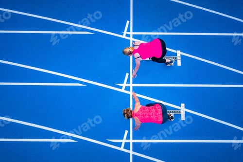 Vista previa: Top view of two female runners starting on tartan track