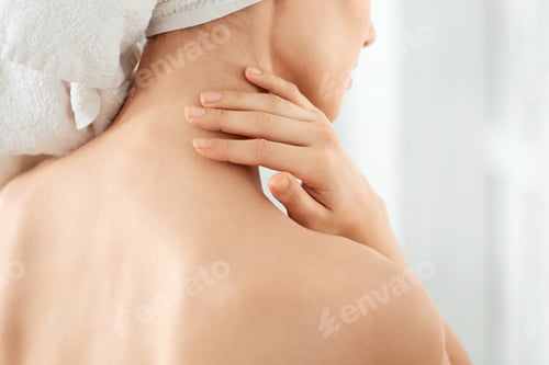 Preview: Young unrecognizable lady wrapped in towel moisturizing her skin