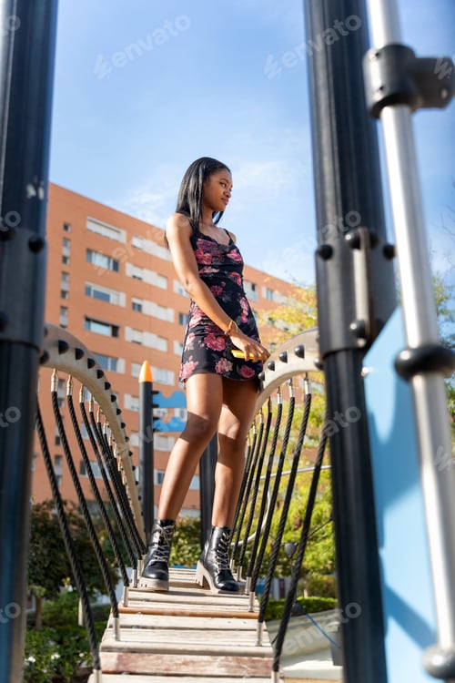 Preview: Young black woman walking on playground bridge in urban setting