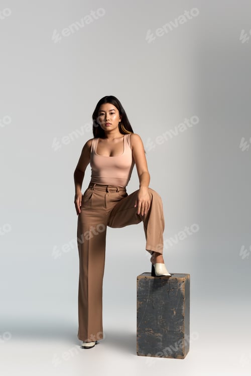 Preview: Asian Woman in Stylish Attire Poses on a Block