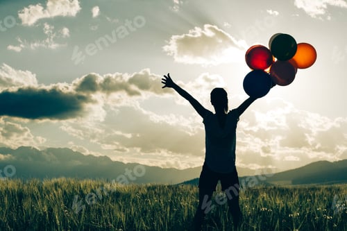 Preview: Happy woman with balloons in the sunset grassland