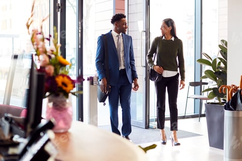 Preview: Businessman And Businesswoman Arriving For Work At Office Walking Through Door
