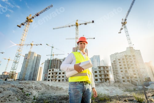 Preview: construction inspector posing with blueprints on building site