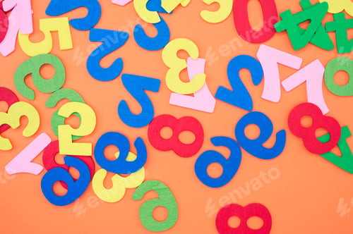 Preview: Top view of the colorful wooden numbers scattered on an orange surface