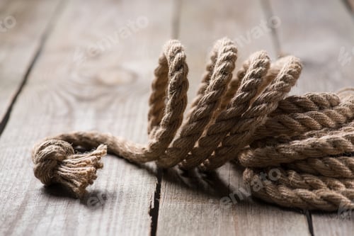 Preview: selective focus of beige knotted nautical rope on wooden background