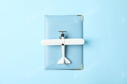 Preview: Passport and toy plane on blue background, top view
