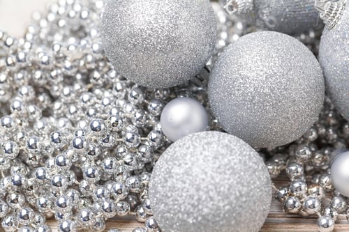 Preview: Shiny silver glitter baubles close up on wooden table