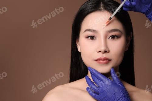 Preview: Woman getting facial injection on brown background
