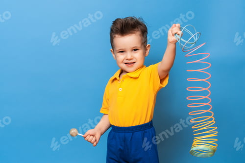 Preview: A boy with a lollipop stands on a blue background of a wall with a toy. Copy space
