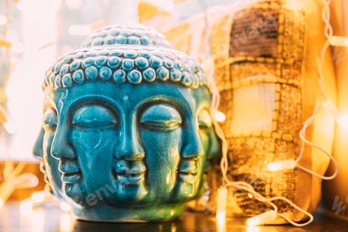 Preview: Blue statue of Buddha head lighted by bokeh boke lights. Interior element