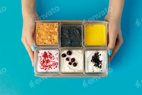 Preview: Mousse desserts in square plastic boxes with different toppings on pink table
