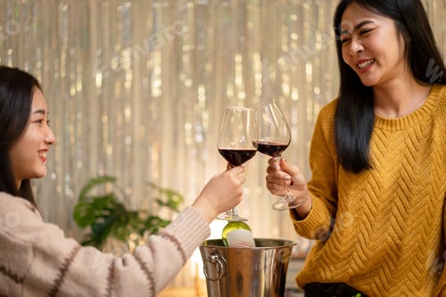 Preview: Young smiling woman drinking and clinking glass of wine to toasting with happiness while celebrating