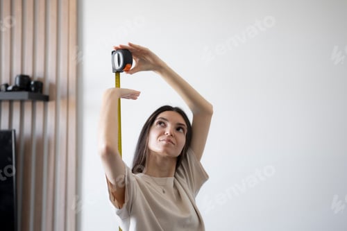 Preview: Young girl Checking Her Height With a Yellow Measuring Tape Indoors