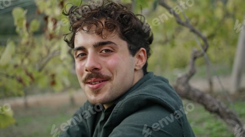 Preview: Portrait man sitting vineyard looking camera with smile. Guy sitting under grape