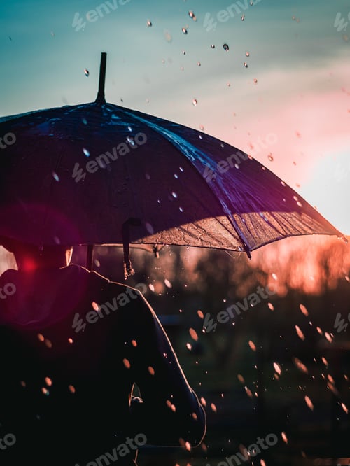 Preview: Male with an umbrella walking in the rain at sunset