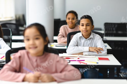 Preview: Portrait of small boy sitting at desk in classroom
