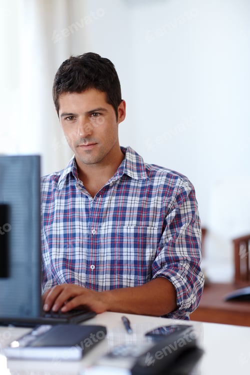 Preview: Hard at work. A young man concentrating while sitting at a desk in front of a computer.