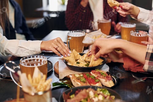 Preview: Delicious food. Group of young friends sitting together in bar with beer