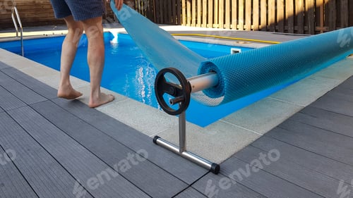 Preview: Man covers swimming pool with cover for protection against dirt, leaves, heating and cooling water.