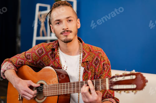 Preview: Young stylish guy musician playing guitar in his apartment