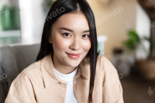 Preview: Close up portrait of smiling asian girl looking happy at camera, sitting at home indoors. Face of