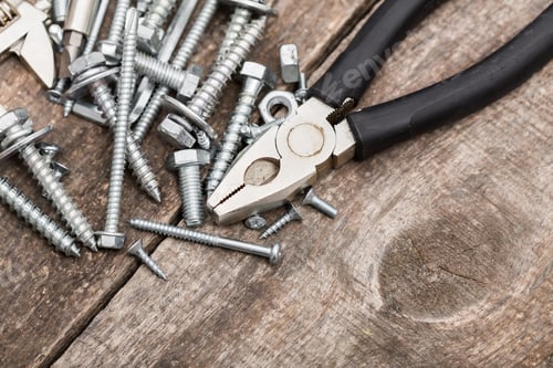 Preview: Various screws and pliers arranged on a wooden surface for a DIY project