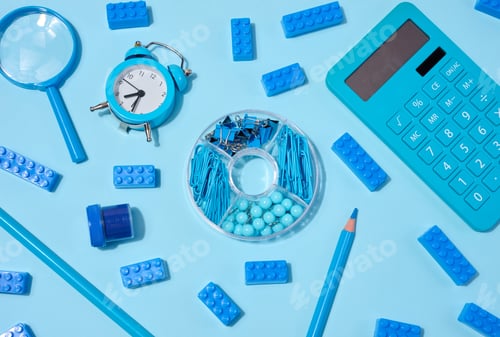 Preview: Flat lay of blue stationery, learning items letters, magnifying glass, supplies, and an alarm clock
