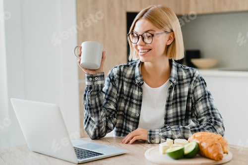 Preview: Woman Enjoys Coffee and Laptop in Bright Kitchen