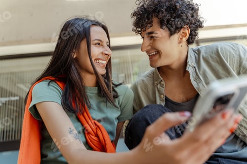 Preview: Young couple sharing a laugh while looking at smartphone