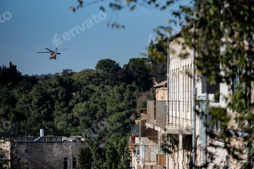 Preview: Landscape of buildings and greenery with a helicopter above it under a blue sky and sunlight