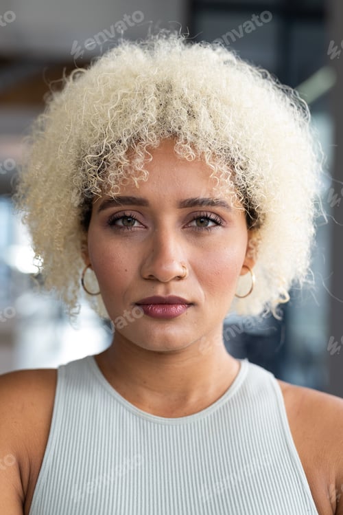 Preview: In modern office, biracial young woman with curly blonde hair standing alone