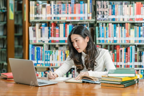 Preview: Asian young Student in casual suit doing homework and using technology laptop in library