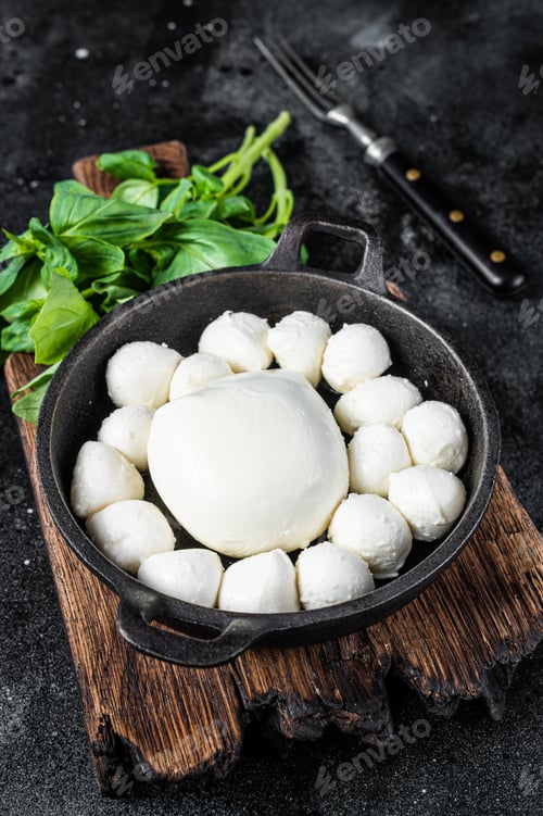 Preview: Mozzarella cheese mini balls in pan with basil. Black background. Top view