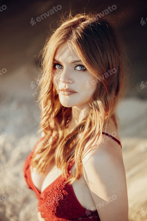 Preview: Beautiful boho girl in red swimsuit posing on sandy beach at sunset light