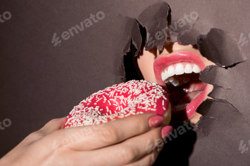 Preview: woman trying to bite donut out of ragged hole in dark paper
