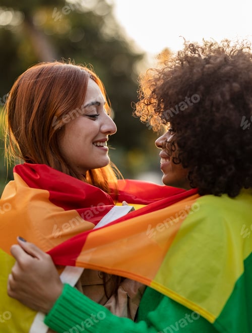 Preview: two lesbian multiracial women wrapped in a rainbow flag