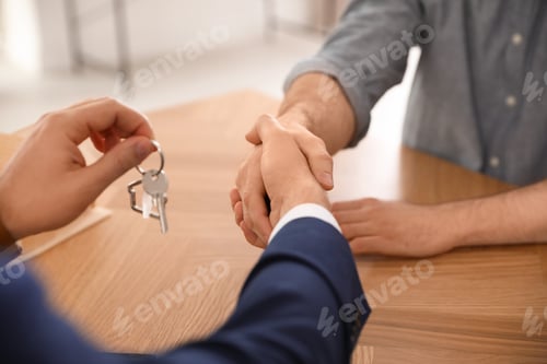 Preview: Real estate agent shaking hands with client in office, closeup