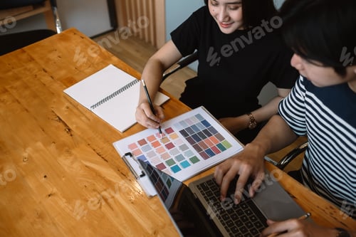 Preview: Group of young designers in casual clothes is using a laptop, discussing affairs.